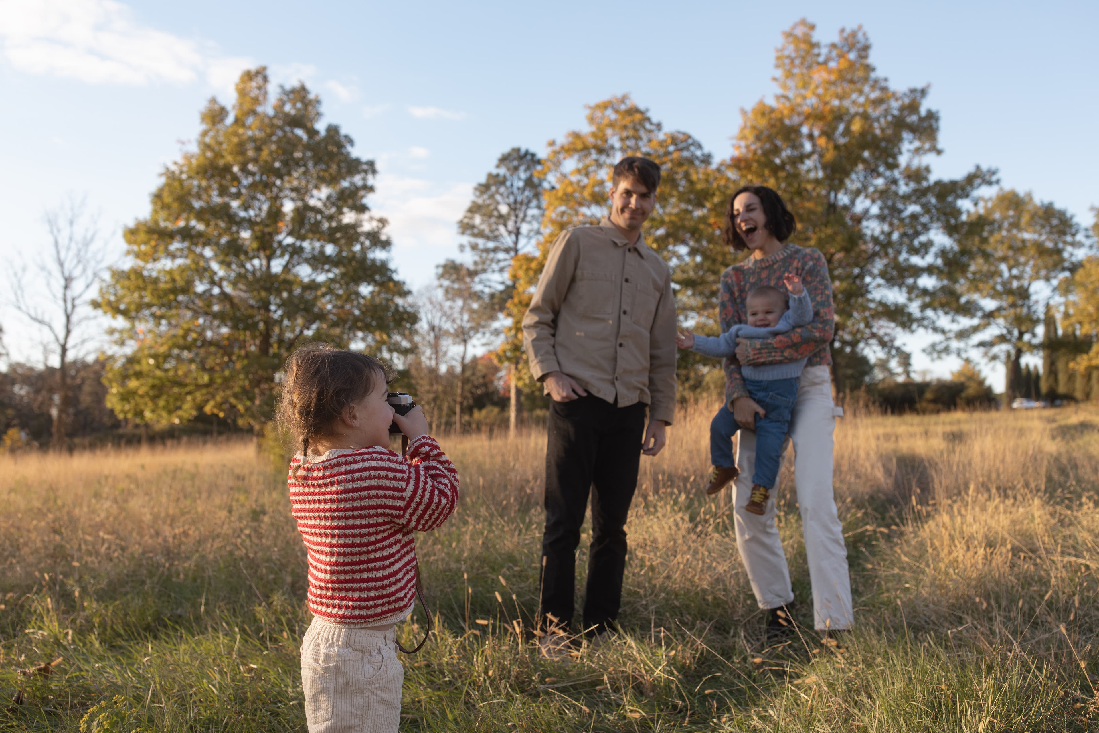 Family in golden field with camera